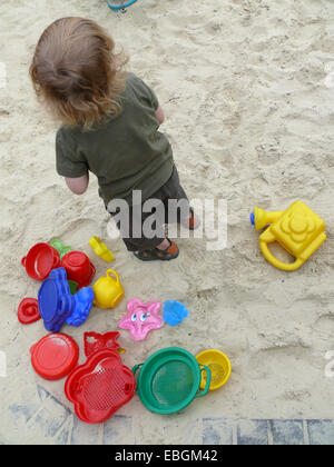 Petit garçon dans l'aire de jeux avec des moules de sable Banque D'Images