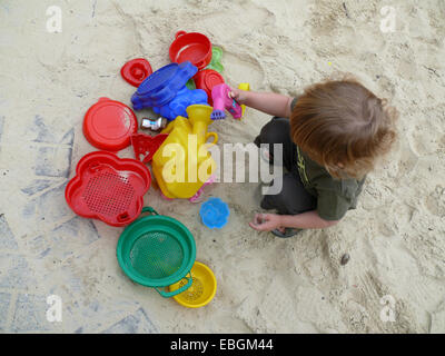 Petit garçon dans l'aire de jeux avec des moules de sable Banque D'Images