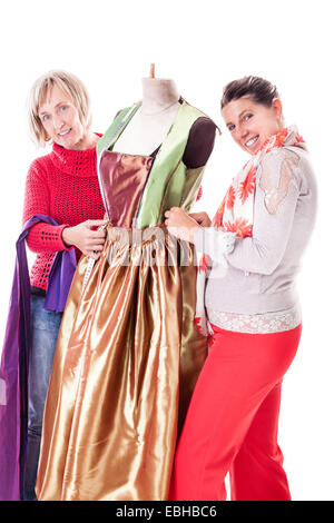 Deux couturières heureux travaillant sur une robe sur un mannequin isolated over a white background Banque D'Images