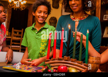 L'éclairage de la famille des bougies, célébrer Kwanzaa kinara Banque D'Images