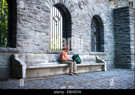 Male student sitting on bench using laptop Banque D'Images