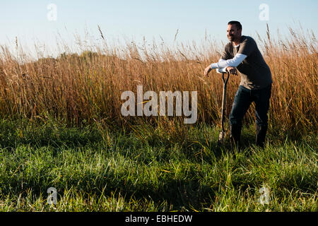 Portrait of mid adult male farmer leaning on chat dans champ, Plattsburg, New York, USA Banque D'Images