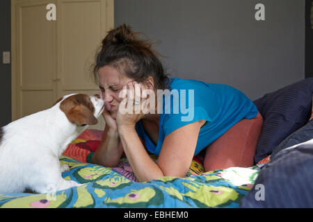 Woman pulling face tout en étant vaincu par chien Banque D'Images