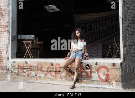 Jeune femme assise sur le mur en disant pas de parking Banque D'Images