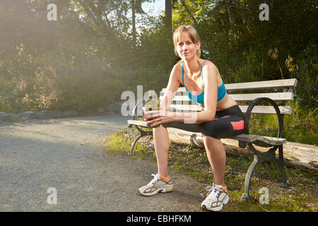 Portrait of smiling female runner Taking a break on park bench Banque D'Images