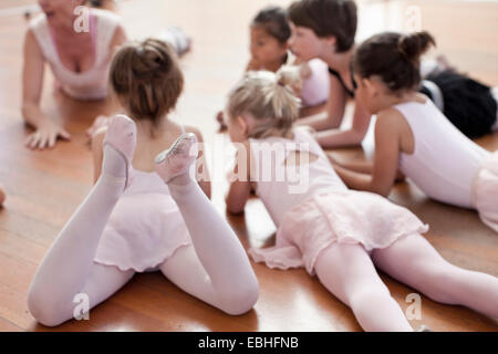 Children lying on floor practicing ballet in ballet school Banque D'Images