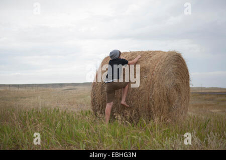 Teenage boy climbing on haystack, South Dakota, USA Banque D'Images