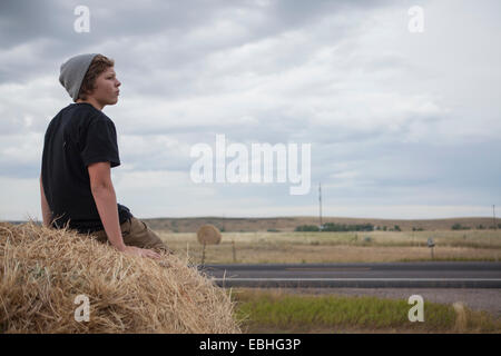 Teenage boy sitting on haystack, South Dakota, USA Banque D'Images