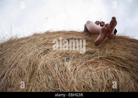 Pieds de teenage boy lying on haystack, South Dakota, USA Banque D'Images