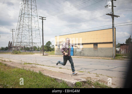 Homme qui court dans la panique le long de la route industrielle, Detroit, Michigan, USA Banque D'Images