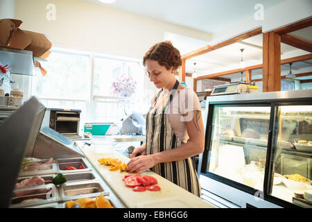 Femme shop assistant slicing fruit en cuisine à country store Banque D'Images