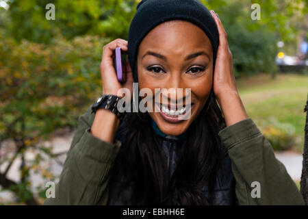 Young woman smiling and holding smartphone à l'oreille Banque D'Images