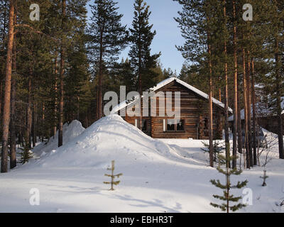 Couvert de neige d'hiver chalet romantique entre les pins dans une résidence de vacances en Laponie, Finlande. Banque D'Images