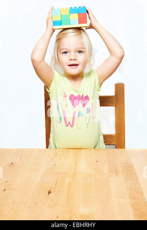 Portrait de petit enfant fille blonde jouant avec des blocs de construction en plastique, fond blanc Banque D'Images