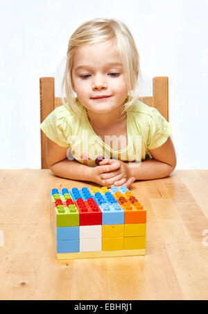 Portrait de petit enfant fille blonde jouant avec des blocs de construction en plastique, fond blanc Banque D'Images