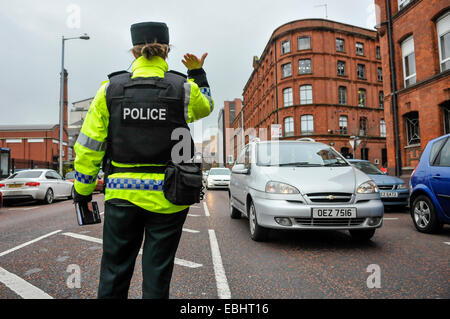 Belfast, Irlande du Nord. 01 déc 2014 - officier PSNI vagues sur le trafic à un point de contrôle temporaire de véhicule. Elle vient après que le CAC sera Kerr prévient que les républicains dissidents sont l'intention de lancer une campagne de bombardements ou tué au cours de la période de Noël. Crédit : Stephen Barnes/Alamy Live News Banque D'Images