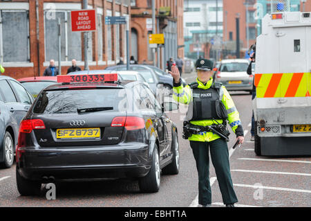 Belfast, Irlande du Nord. 01 déc 2014 - officier PSNI vagues sur le trafic à un point de contrôle temporaire de véhicule. Elle vient après que le CAC sera Kerr prévient que les républicains dissidents sont l'intention de lancer une campagne de bombardements ou tué au cours de la période de Noël. Crédit : Stephen Barnes/Alamy Live News Banque D'Images