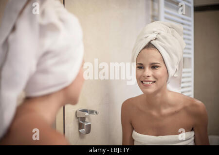 Young woman wearing towel on head à la réflexion au miroir dans Banque D'Images