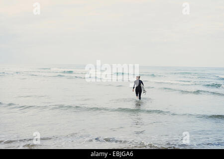 Surf surfer avec la marche dans l'océan, Lacanau, France Banque D'Images