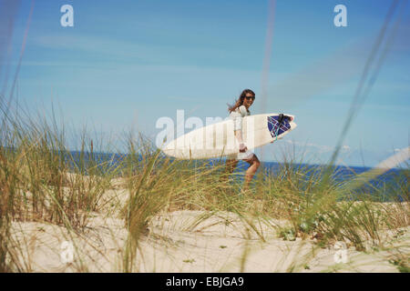 Woman with surfboard on beach, Lacanau, France Banque D'Images