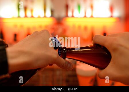 Un homme s'ouvre une bouteille de bière avec une autre bouteille dans un bar avec un ouvre-bouteille, Allemagne, ville d'Osterode, 21. Novembre 2014. Photo : Frank May Banque D'Images