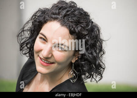 Un portrait d'une jeune femme au début de la vingtaine. Elle a les cheveux noirs et elle porte un haut noir. Banque D'Images