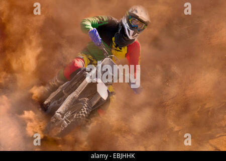 Jeune homme motocross rider course dans la poussière Banque D'Images