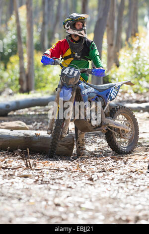 Jeune homme motocross racer standing in forest Banque D'Images