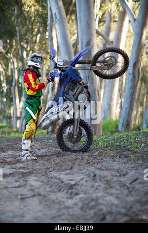 Jeune homme racer motocross moto avec commandes sur piste en forêt Banque D'Images