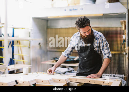 Cropped shot of mid adult craftsman mesurant en bois atelier d'organes Banque D'Images