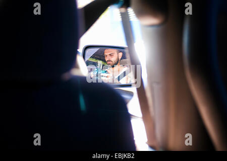 Reflet de jeune homme dans le rétroviseur de voiture Banque D'Images