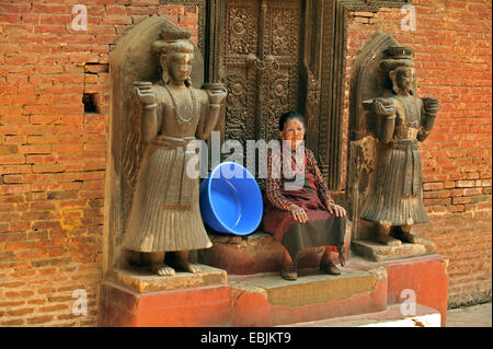 Portrait d'une vieille femme en face d'une porte en bois du palais du roi orné de sculptures, Népal, Patan Banque D'Images