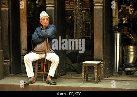 Vieil homme coin sur une chaise en face d'une boutique, Népal, Patan Banque D'Images