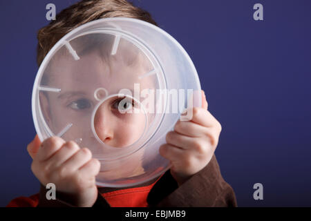 Boy looking through seau plastique Banque D'Images