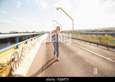 Jeune femme marchant sur Bridge à la recherche en sac d'épaule Banque D'Images