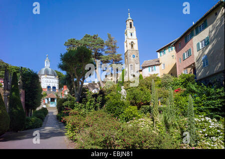 Fil par les chemins d'arbustes, fleurs et arbres en place batterie Portmeirion village dominé par les bâtiments de style italien Banque D'Images