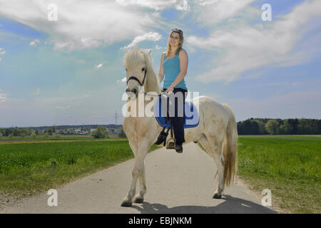 Islandic Horse, cheval islandais, Islande pony (Equus przewalskii f. caballus), jeune fille à cheval à travers une forêt et prairie paysage sur un poney, Allemagne, Bavière, Oberpfalz Banque D'Images