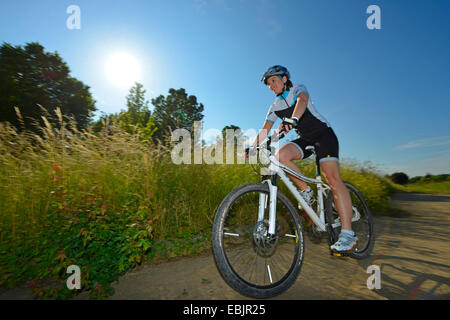 Vélo de montagne femelle sur une route à travers la forêt et prairie paysage, Allemagne, Bade-Wurtemberg Banque D'Images