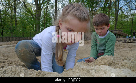 Petit garçon et petite fille jouant dans le sable sur une aire de jeux Banque D'Images