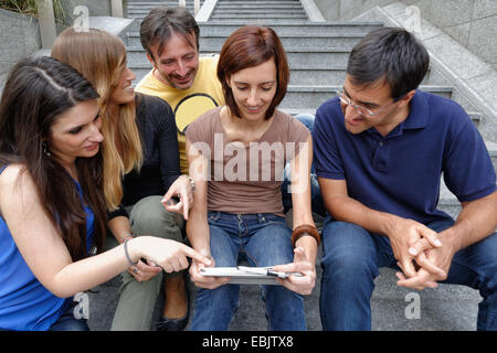 Groupe d'amis looking at digital tablet Banque D'Images