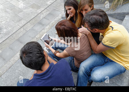 Groupe d'amis looking at digital tablet, vue arrière Banque D'Images