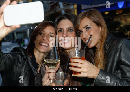 Trois amies en bar, taking self portrait using smartphone Banque D'Images