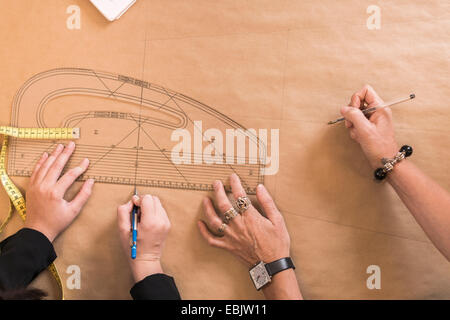 Vue aérienne de couturières mains dessin avec panneaux de la règle modèle de l'atelier de couture Banque D'Images