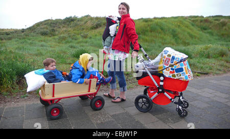 Mère de trois enfants, la pram et charrette sur un chemin des dunes Banque D'Images