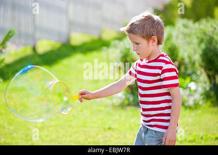 Garçon sympathique faisant des bulles de savon dans le jardin Banque D'Images