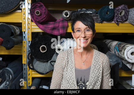 Portrait of mature couturière en face de rouleaux de textile en atelier Banque D'Images