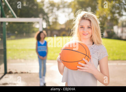 Portrait of young woman holding up basket-ball Banque D'Images