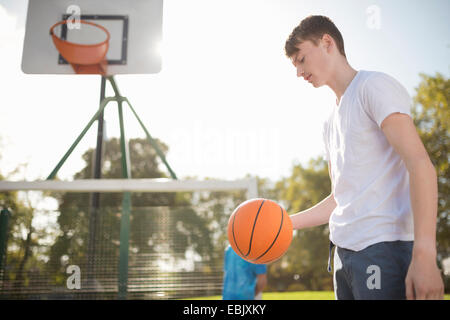 Jeune joueur de basket-ball masculin sur cour avec le basket-ball Banque D'Images