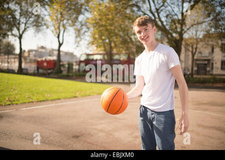 Portrait of smiling young male basketball player holding basketball Banque D'Images