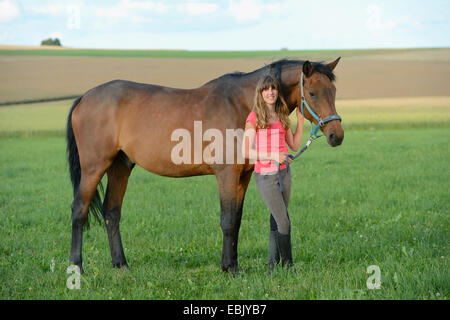 Chevaux hanovriens, warmblood allemand (Equus przewalskii f. caballus), jeune fille à cheval dans un pré, Allemagne Banque D'Images